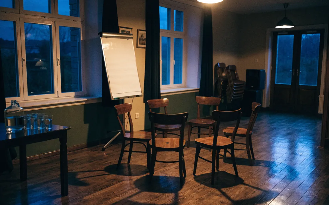 Świetlica przygotowana na spotkanie: krzesła ustawione w krąg, flipchart, dzbanek z wodą.